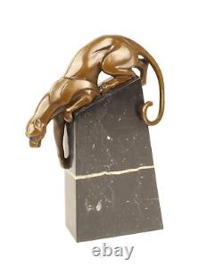 A bronze sculpture of a descending panther on a black marble signed