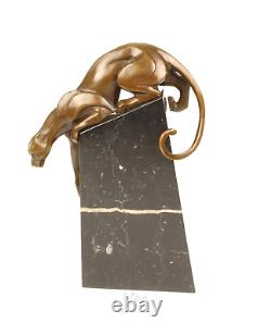 A bronze sculpture of a descending panther on a black marble signed