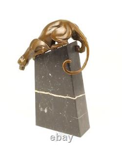 A bronze sculpture of a descending panther on a black marble signed