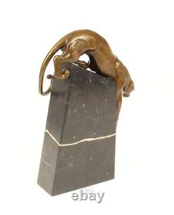 A bronze sculpture of a descending panther on a black marble signed