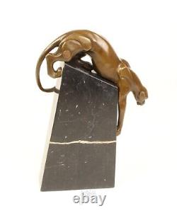 A bronze sculpture of a descending panther on a black marble signed