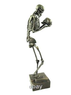 Antique bronze skeleton figurine on black marble