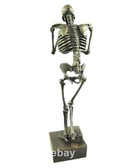 Antique bronze skeleton figurine on black marble