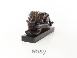Bronze cougar statue by the pool on a black marble base, signed