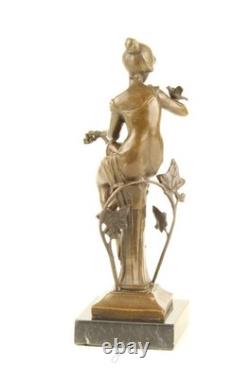 Bronze sculpture of a seated lady with a bird on a black marble base after Nick