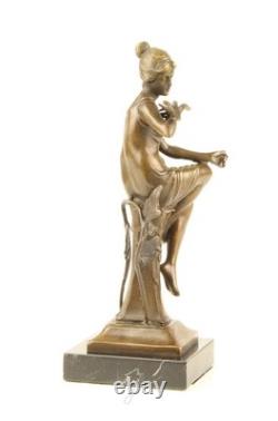 Bronze sculpture of a seated lady with a bird on a black marble base after Nick