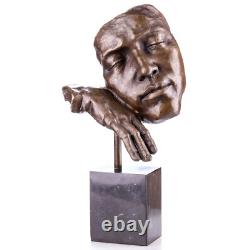 Face statue with a bronze hand on a black marble pedestal after S. Dali