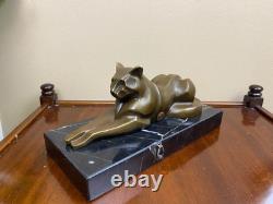 Sculpture of a modern reclining cat on black marble by Michel Decoux