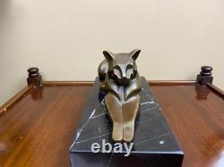 Sculpture of a modern reclining cat on black marble by Michel Decoux