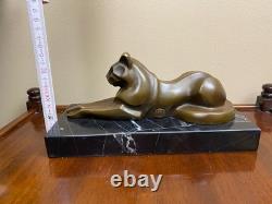 Sculpture of a modern reclining cat on black marble by Michel Decoux