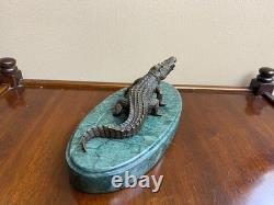 Shared bronze crocodile sculpture on a green marble base after Milo